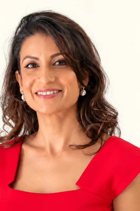 Mitali Saxena in a red dress against a light background, smiling
